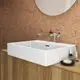 Weißer Waschtisch von Ideal Standard mit eckigem Becken, Wandmontage und Armatur. Holzunterbau und pflegeleichte Oberfläche vor einem Korkmuster.